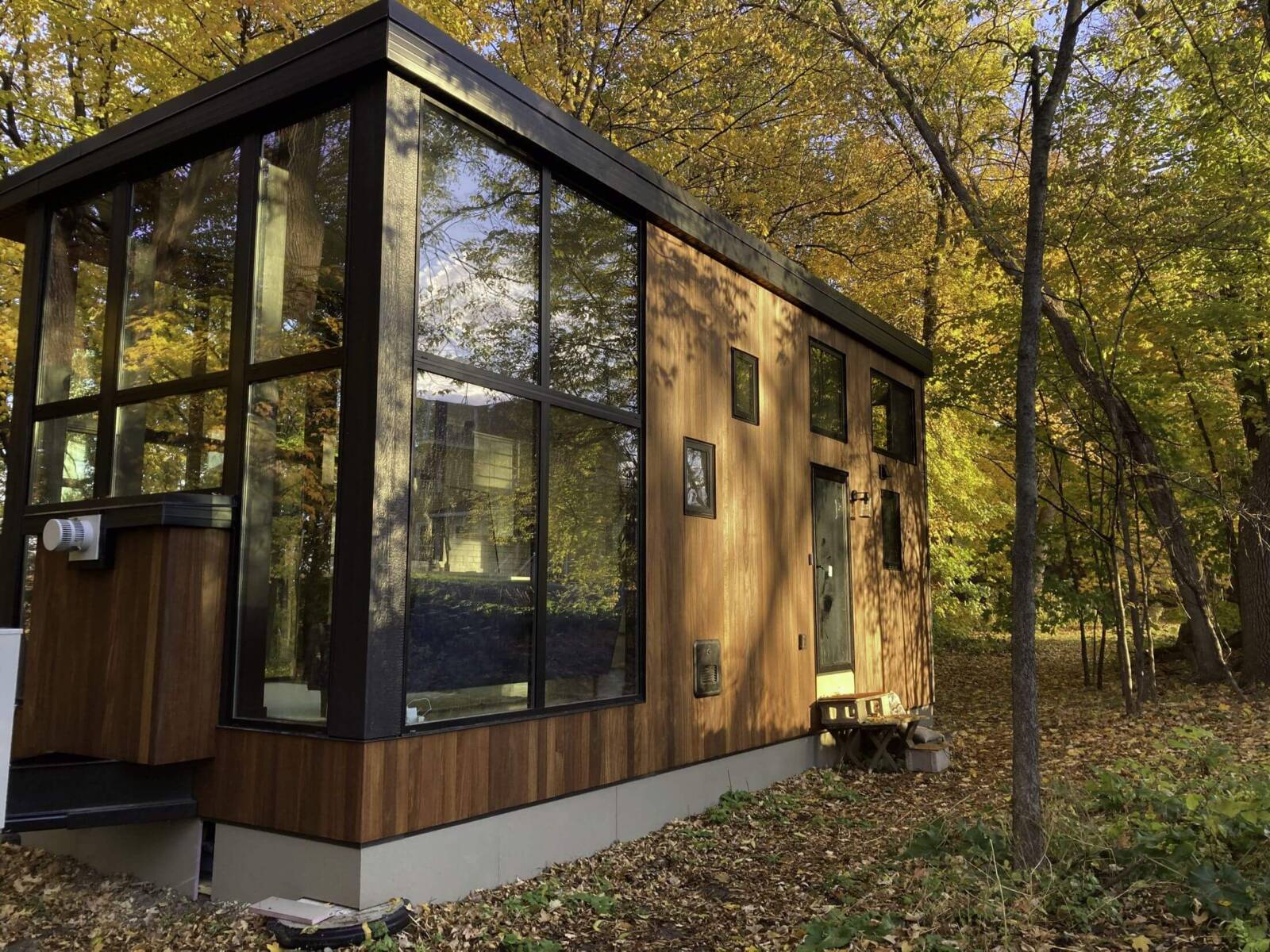 Modern tiny home with floor-to-ceiling windows in a forest setting